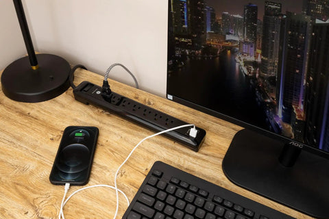 Dope UltraPro 7 Outlet Surge Protector With USB Ports on desk, 4 foot cord, black, powering monitor and charging phone.