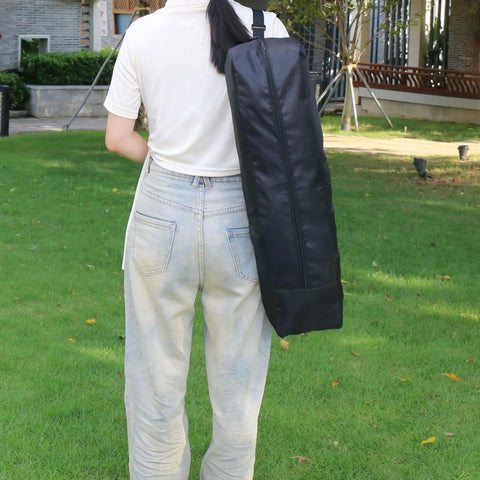 Back view of person carrying a Rugged Multi-Function Equipment Organizer Bag For Music Stands Tripods Mic Stands Camera Gear And Hunting Kit Heavy Duty Water-Resistant Storage Case Travel Tool Kit 22 Inches Long With Adjustable Dividers For A Custom Fit.