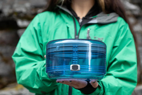Person holds Adjustable Bear Canister For Backpacking And Camping, Expands And Collapses For Bear Resistant Food Storage