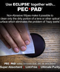Eclipse optic cleaning solution used to wipe a round camera lens with a white microfiber cloth on a wooden surface.