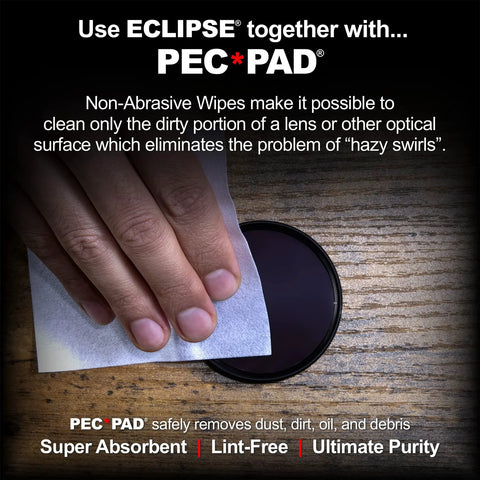 Eclipse optic cleaning solution used to wipe a round camera lens with a white microfiber cloth on a wooden surface.
