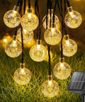 Solar String Lights For Outdoor 20Ft 30 LED Crystal Globe Fairy Lights Warm White With 8 Lighting Modes on grass.