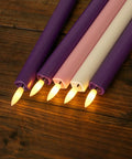 Flickering Flameless Taper Candles With Remote, 10 Inch LED Candlesticks in purple, pink, and ivory on wood surface