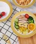 Sturdy Reusable Plastic Bowls With Gleaming Gold Grid Rim, 12 Ounce White Bowls featuring colorful food on a tabletop.