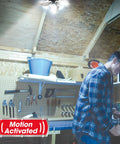 Motion Activated Garage Light With 96 Ultra Bright LEDs, 6000 Lumens, illuminating a workshop with a person working.