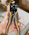 Hand holding 5 In 1 Self Adjusting Wire Stripper Kit with Automatic Wire Stripper for AWG 24 to 10, showcasing gripped handles