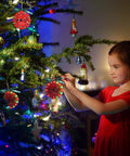 Child hanging Starter Soldering Kit for Christmas Projects with LED Light Up Tree Decor on a Christmas tree branch.