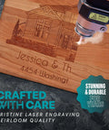 Front view of a wooden cutting board with laser-engraved house illustration and personalized names