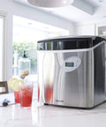 Portable Countertop Ice Maker Delivers 12 Bullet Ice Cubes in 7 Minutes, 50 Lb Daily Capacity, stainless steel finish on kitchen counter.
