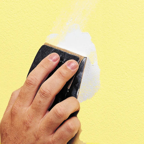 Applying spackling on yellow wall, smoothing surface for interior and exterior use with dry time indicator ensuring crack resistance.