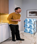 Man in kitchen with Heavy Duty 3 Tier 5 Gallon Water Jug Rack, Steel Water Bottle Dispenser Stand With Six Slots