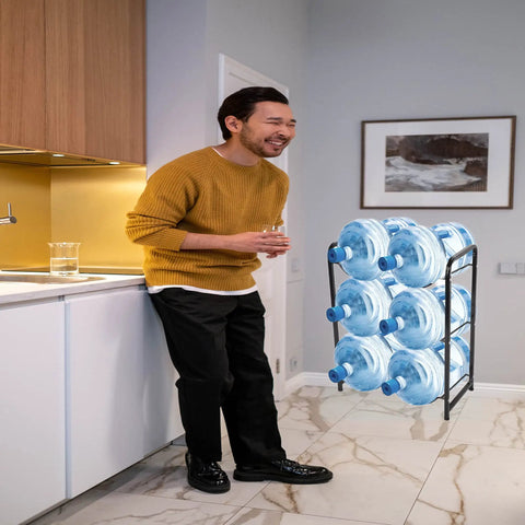 Man in kitchen with Heavy Duty 3 Tier 5 Gallon Water Jug Rack, Steel Water Bottle Dispenser Stand With Six Slots