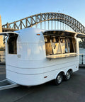 Ready To Roll 13 Foot Vintage Food Trailer With Fully Equipped Mobile Catering Kitchen And Slick White Exterior, side view near bridge.