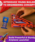 Hands assembling DIY Paper Airplane Craft Kit With Launcher, 50 Planes In 5 Designs, STEM Fun For Kids Ages 6 Plus on wooden table.