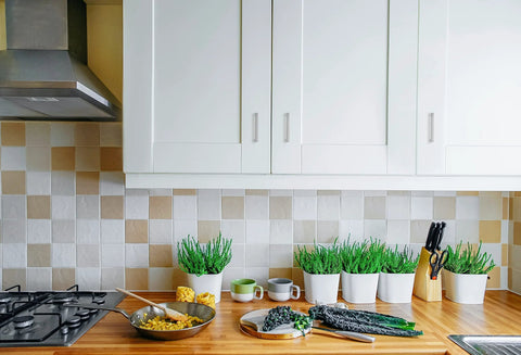 White kitchen cabinets with 30 Pack Solid 3 Inch Center To Center Slim Square Bar Drawer Handles In Brushed Nickel mounted above a wooden countertop.