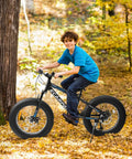 Smiling boy riding Fat Tire Mountain Bike For Kids 20x4 Inch With Dual Disc Brakes Suspension Fork 7 Speed in autumn leaves.
