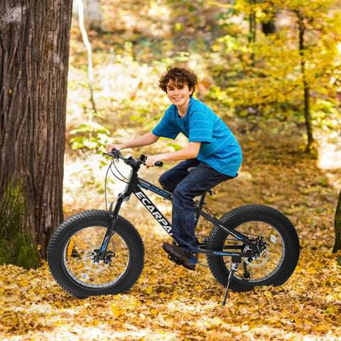 Smiling boy riding Fat Tire Mountain Bike For Kids 20x4 Inch With Dual Disc Brakes Suspension Fork 7 Speed in autumn leaves.
