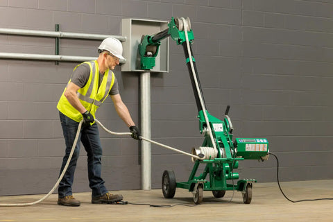 Man operating Greenlee 10k Tugger Package Featuring Dual Speed Motor For Faster Pulls with footswitch in safety gear.