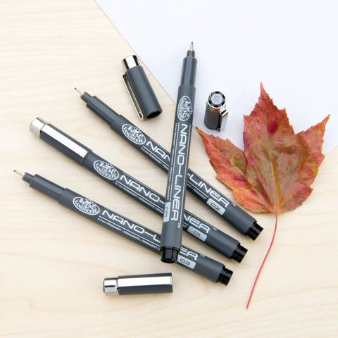Nano Liner Drawing Pen Set Black 4 Pack Fine Point Nibs 0.1 0.2 0.3 0.5 Mm Pro Grade Ink Flow on wooden surface with leaf