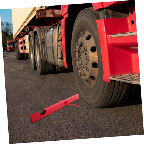 Red Manual Strap Winder For Trucks placed on asphalt next to a truck tire, Hand Crank Cargo Belt Winder Tool ready for use