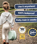 Girl carrying a green pastel travel potty, Leak Proof Portable Toddler Toilet Seat For Potty Training, on a walking path.