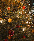 Decorated Christmas tree with lights and ornaments featuring red baubles and star-shaped decorations, glowing in a festive setting.