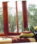 Cozy window seat with pillows and plants overlooking forest view