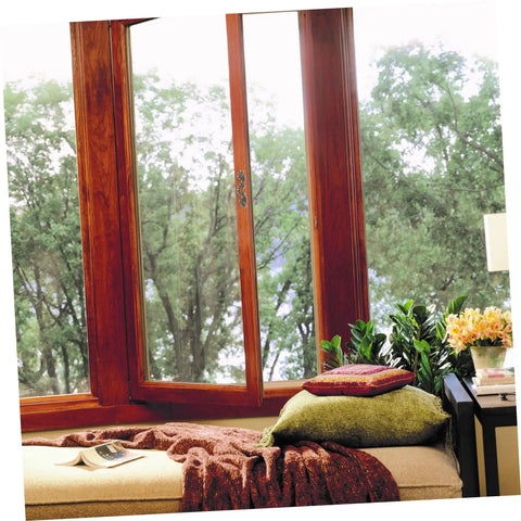 Cozy window seat with pillows and plants overlooking forest view