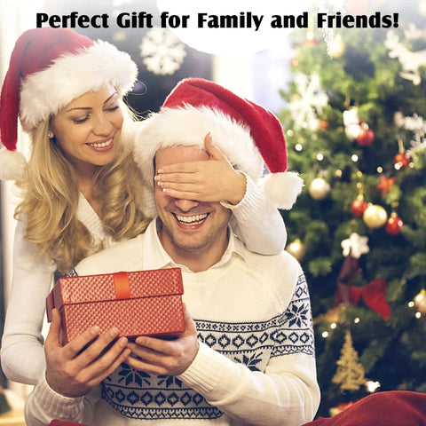 Couple in festive hats exchanging a gift by a decorated Christmas tree