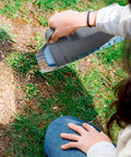 Spot Spreader 80 Oz Handheld Grab-And-Go Dispenser For Salt Seeds Grass And Garden Use in action on a grassy patch.