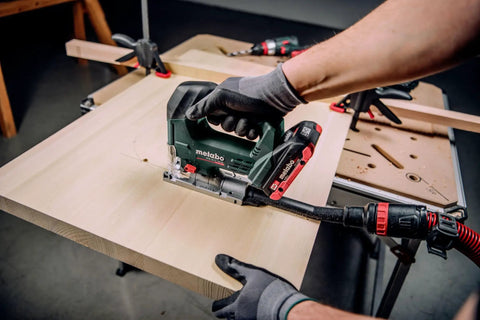 Heavy Duty Knockout 18V Brushless Cordless Jigsaw cutting through wood on a worktable, showcasing ergonomic grip and precision.