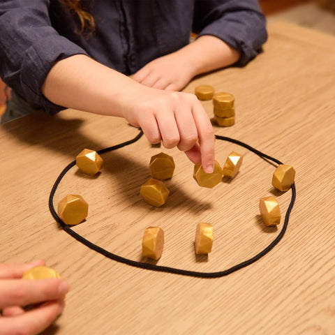 Child playing Magnetic Strategy Party Board Game For Family Night With 20 Magnets, Rope, And Easy Instructions on table.