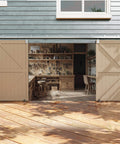 Installed Exterior Sliding Barn Door Hardware Kit With Beefy Box Rail Heavy Duty 20 Foot Silver Finish Galvanized Steel on gray wood building.