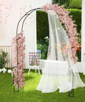 7.9 Ft Metal Garden Arch Trellis For Climbing Plants Like Roses And Clematis in black with pink flowers and draped fabric outdoors