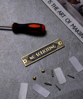 Brass No Soliciting Sign Six Point Five Inch Classic Art Deco Style with tools, screws, and nanotape on gray surface.