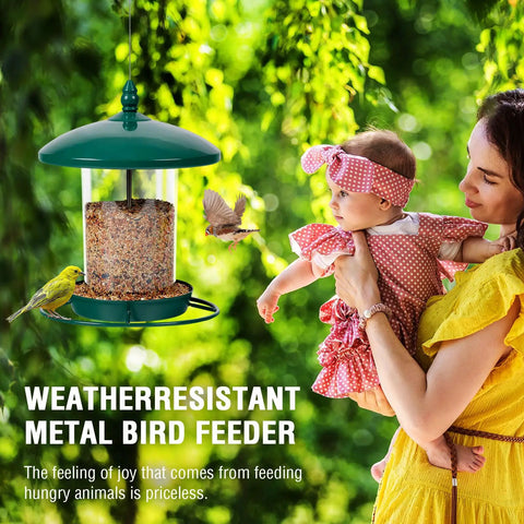 Green chew proof metal bird feeder outdoors with 3 lb seed capacity, woman holding baby next to feeding birds in garden