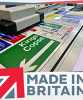Printing machine producing various signs with text, including green 'Kings Copse' direction sign.
