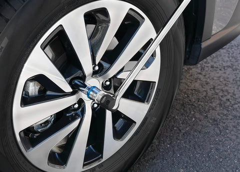 Using 1/2 Inch Drive Ratcheting Breaker Bar Adapter to remove a car tire lug nut with reversible mechanism, Taiwan-made tool in action.