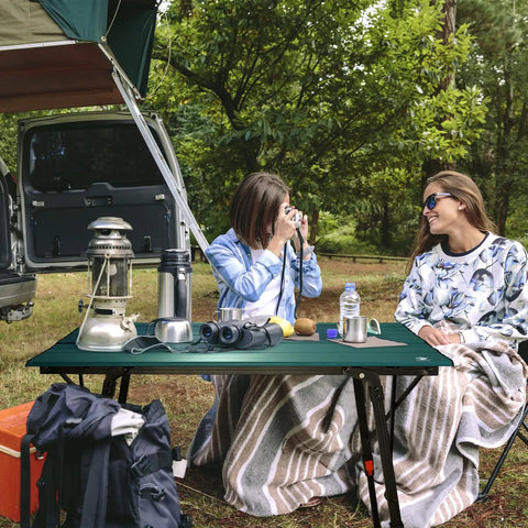 Two campers sitting by Ultra Lightweight Aluminum Folding Camping Table With Adjustable Legs Portable Beach And Picnic Table outdoors