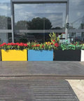 Multi-colored rectangular planter boxes with flowers on a patio, including 40 Inch Long Metal Rectangular Planter Box For Outdoor Patio Porch Black Modern Design Built To Last No Tool Needed Quick Snap In Planter For Plants Flowers Garden Heavy Duty Outdoor Box For Deck Balcony.