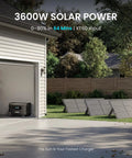 Guardian 6000 V2 Portable Power Station 120V 240V Dual Voltage with solar panels in a yard next to an open garage.