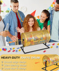 Gold metal raffle drum on black stand with wooden handle; group at party with colorful tickets