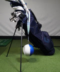 Compression Ball Golf Swing Trainer For Perfect Impact And Forearm Connection next to golf bag on indoor turf floor