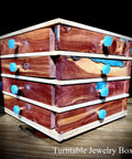 Wooden turntable jewelry box with turquoise knobs on a dark background.