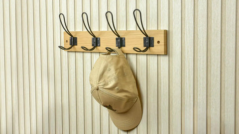 Super Sturdy Wall Mounted Coat Rack With Four Heavy Duty Hooks To Keep Clutter In Check Holds a cap on a wooden rack.