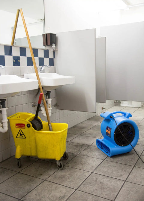 One Half Horsepower Heavy Duty Air Mover, Lightweight Carpet Dryer and Floor Blower in a restroom next to a mop bucket