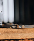 Solid As A Rock Pocket Folder With 2 Inch Clip Point Blade Crafted From High Carbon Stainless Steel And Rough Cut Sawcut Grip on wood.