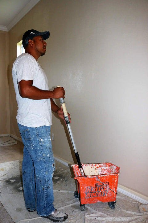 Person using RBC-323 Roll A Bucket With 3 Inch Caster Wheels And Brake 6 Gallon Orange Rolling Bucket For Paint And Tarps.