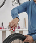 Person using Diagonal Flush Cutter For Plastics with 45 degree angle blades on a bicycle tire for precision cutting, red handle visible.