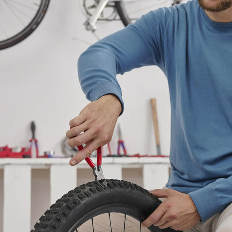 Person using Diagonal Flush Cutter For Plastics with 45 degree angle blades on a bicycle tire for precision cutting, red handle visible.